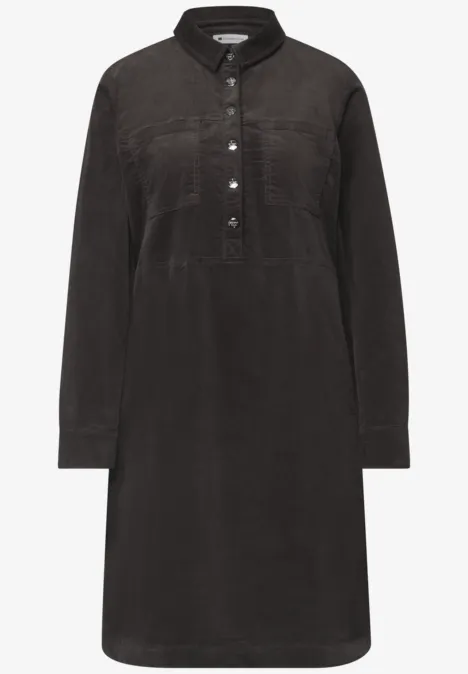Robe-chemise en velours côtelé noir, col chemise, demi-patte de boutons, poches poitrine et manches longues.