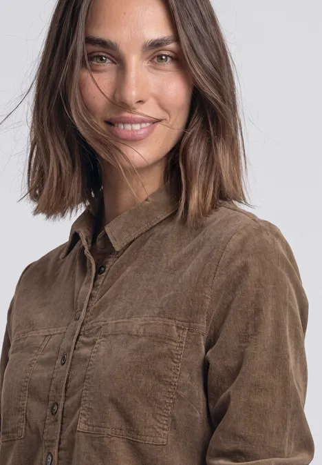 Knielanges Kleid aus softem Cord velvet mocha Eine lächelnde Frau mit schulterlangem braunem Haar trägt ein braunes Cord-Hemd.