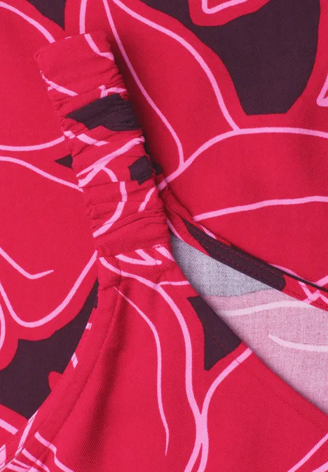 Robe mi-longue à bretelles froncées salsa red Gros plan d’un tissu rouge à motifs floraux noirs et blancs stylisés avec une couture apparente.