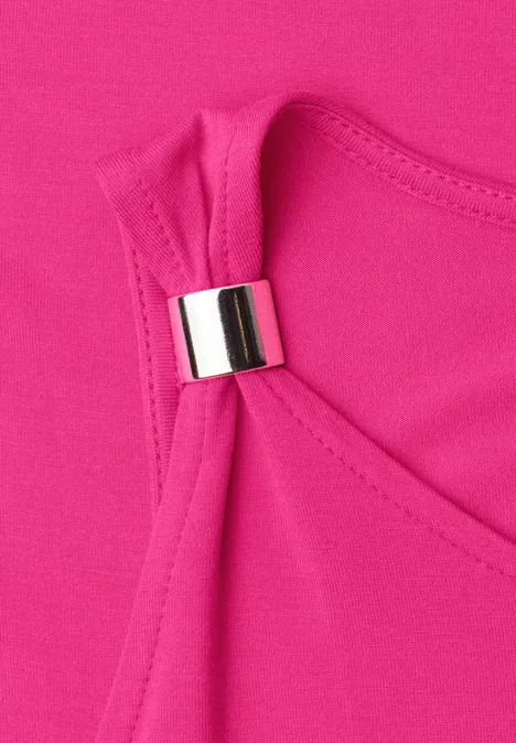 Detailaufnahme eines pinken Oberteils mit metallischem Ring am Träger.