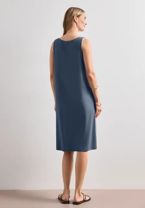 Knielanges Kleid mit Schnallendetail ashen blue Frau in ärmellosem, knielangem, marineblauem Kleid vor neutralem Hintergrund.