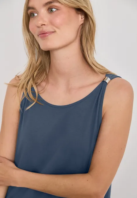 Knielanges Kleid mit Schnallendetail ashen blue Eine junge Frau mit hellblonden Haaren und blauem Trägertop, leicht seitlich im Studio posiert.