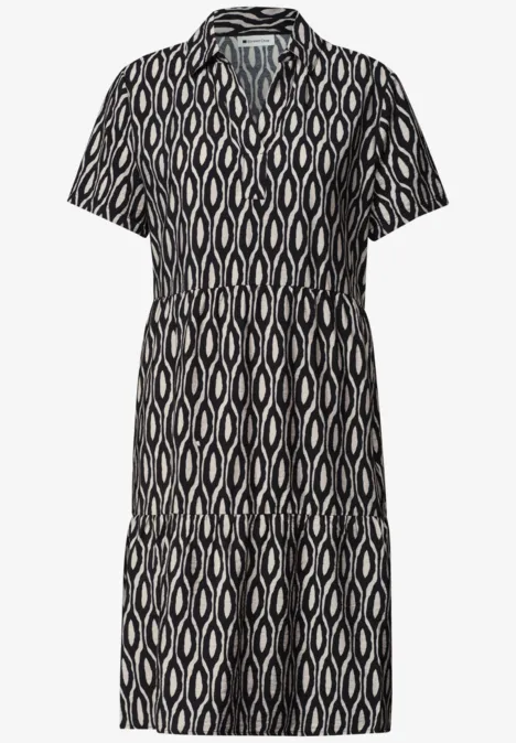 Schwarz-weiß gemustertes Hemd-Kleid mit Kragen, kurzen Ärmeln und stufigem Rockansatz.