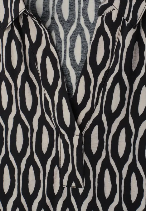 Schwarzer Stoff mit weißem, ovalem Ikat-Muster.