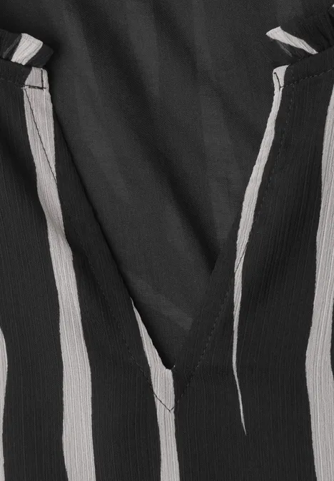 Gros plan sur un tissu noir à rayures blanches et un col en V.