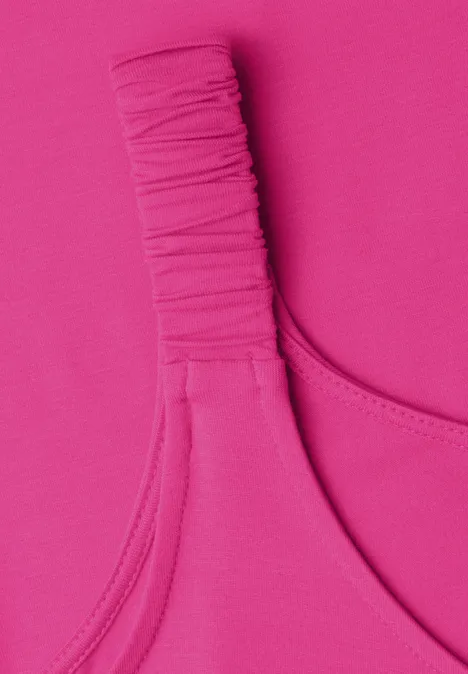 Nahaufnahme eines pinkfarbenen Kleidungsstücks mit gerafftem Träger.
