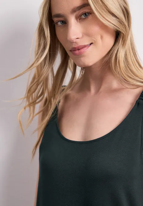 Nahaufnahme einer lächelnden Frau mit blonden Haaren und schwarzem ärmellosem Top.