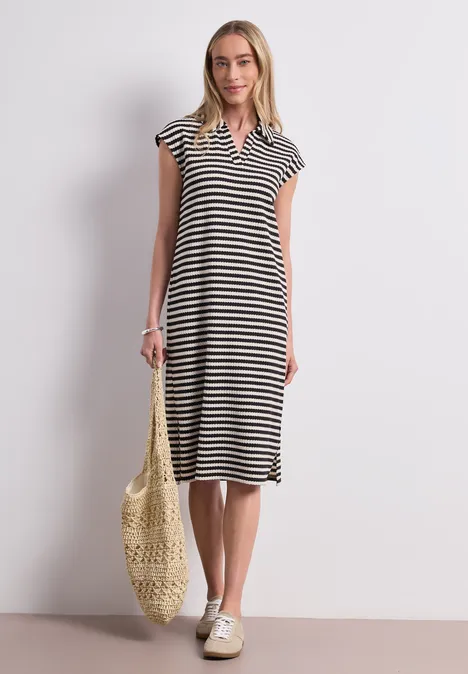 Femme en robe midi à rayures, col V, avec sac en filet et baskets.