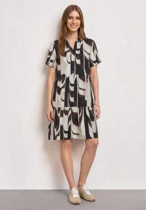 Knielanges Kleid mit Kurzarm und Print espresso brown Frau in knielangem Schwarz-Weiß-Kleid mit abstraktem Muster und weißen Sneakern vor hellem Hintergrund.