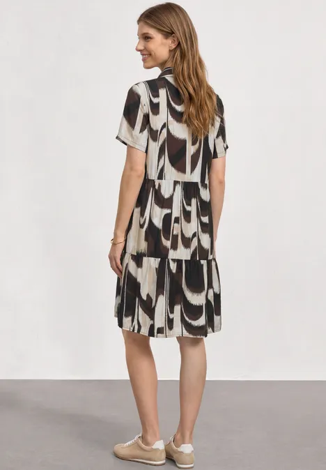 Knielanges Kleid mit Kurzarm und Print espresso brown Frau von hinten in kurzärmligem, lockerem Kleid mit schwarz-weißem Muster und Turnschuhen.