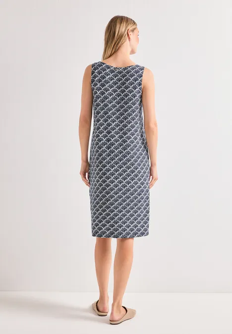 Frau von hinten in ärmellosem, knielangem Kleid mit blau-weißem Rautenmuster.