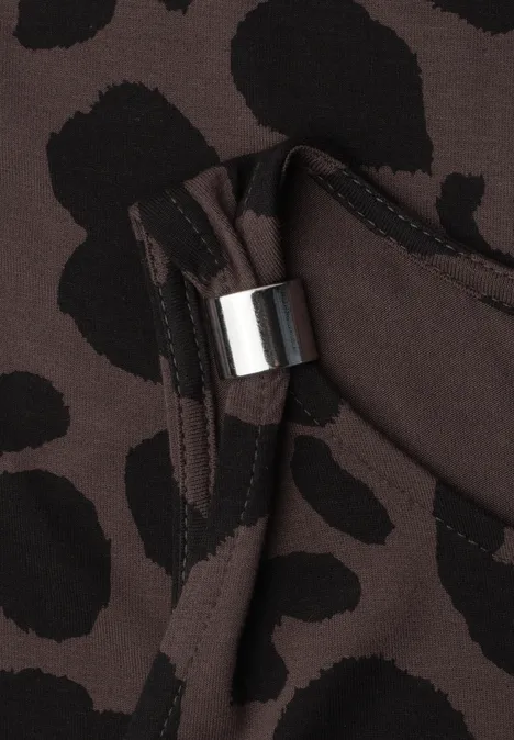 Braunes Textil mit schwarzem Leopardenmuster, Tasche und silbernem Metallelement.