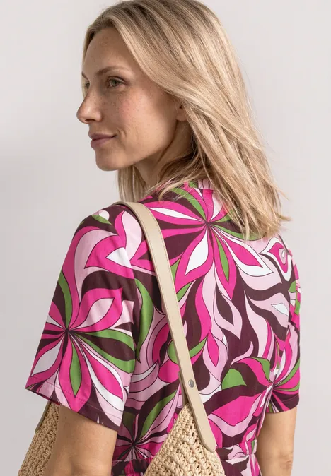 Midi-Kleid mit V-Neck und Print magenta dream Blonde Frau trägt auffälliges T-Shirt mit buntem Blumenmuster und eine Strohtasche über der Schulter.
