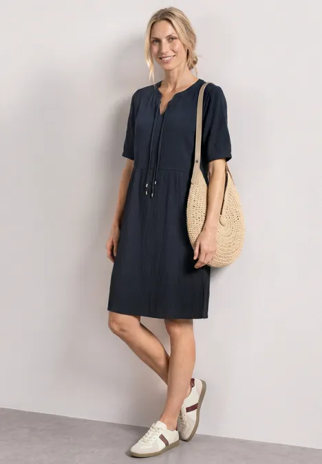Knielanges Kleid mit Schleifendetail darkest blue Frau im navyblauen Kurzarmkleid mit weißen Sandalen und großer geflochtener Tasche.