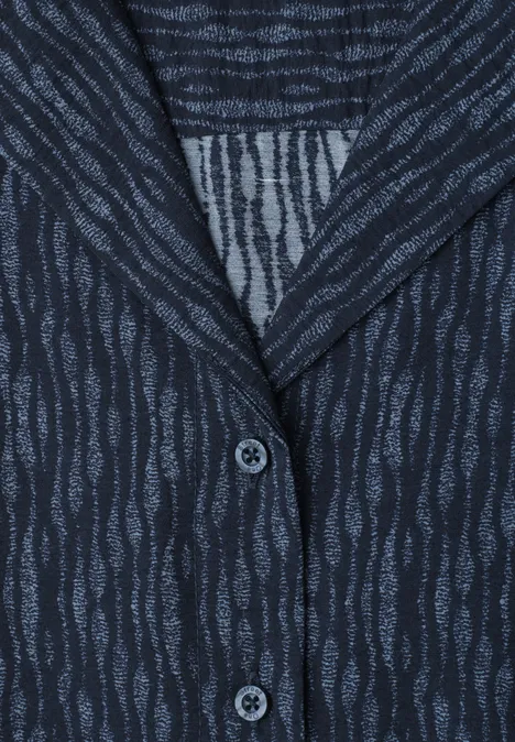 Gilet ou chemise bleu foncé à motif ondulé et fermeture boutonnée sur la poitrine.