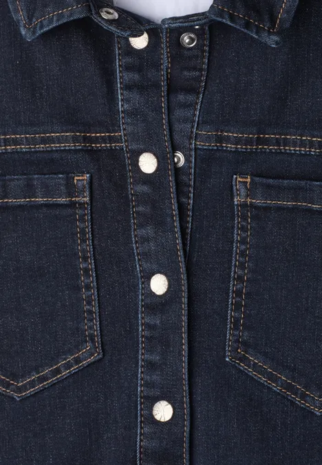 Dunkelblaue Jeansjacke mit silbernen Druckknöpfen und zwei Brusttaschen in Nahaufnahme.