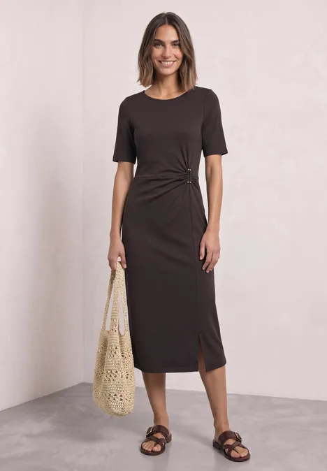 Midijurk van jersey met wikkel-look black coffee Vrouw draagt bruin nauwsluitend midijurk met zijsplit, gehaakte tas en platte sandalen.