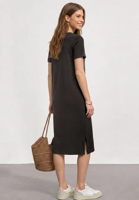 Midikleid in Rippstruktur mit Rundhals black coffee Frau von hinten in knielangem, schwarzem T-Shirt-Kleid und weißen Sneakers, mit Korbtasche