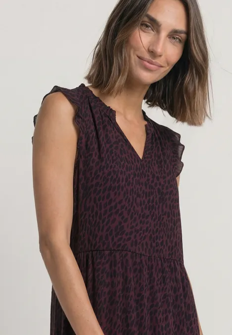 Femme aux cheveux mi-longs porte une robe sans manches à imprimé léopard violet et encolure en V.