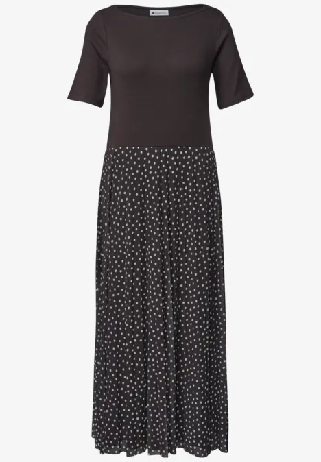 Schwarzes Kleid mit halblangen Ärmeln und gepunktetem, fließendem Rock.