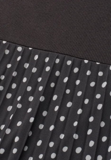 Schwarzer, gerippter Oberstoff und plissierter Rock mit weißen Polka Dots