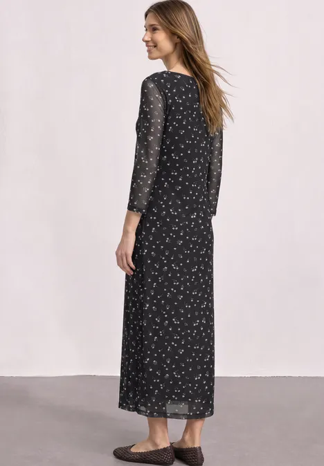 Femme de dos portant une robe longue noire à petits motifs floraux