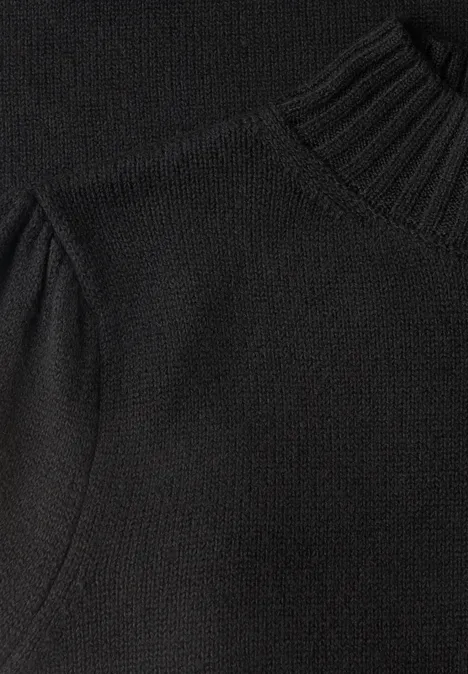 Gros plan d'un pull en maille noire à col montant.