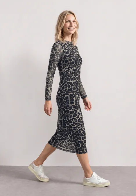 Midikleid mit Boat Neck und Leo-Print Black Eine Frau in seitlicher Pose trägt ein knielanges, langärmeliges, gemustertes Kleid und weiße Sneaker.