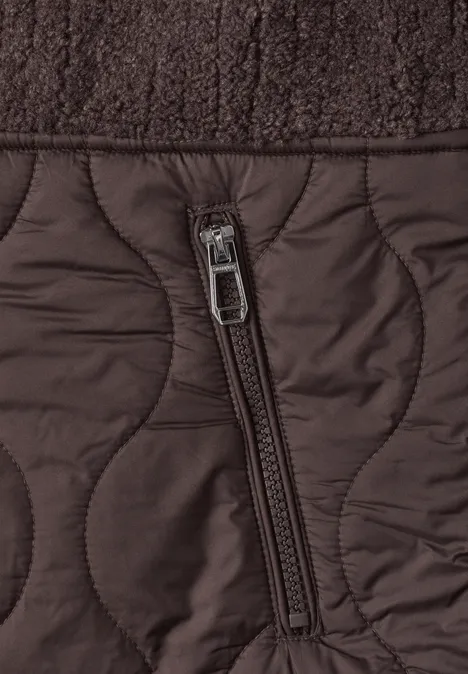 Nahaufnahme einer braunen Steppjacke mit Ziersteppung und seitlichem Reißverschlussfach.