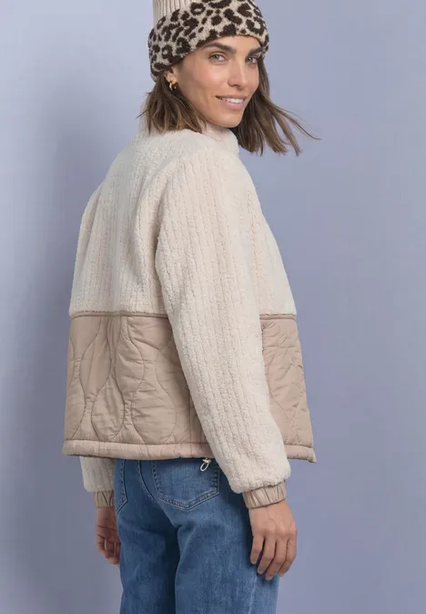Teddyjas met softshell-details Soft Fawn Beige Frau trägt wattierte Jacke in Beige und Creme, kombiniert mit Leopardenmuster-Tuch und Jeans.