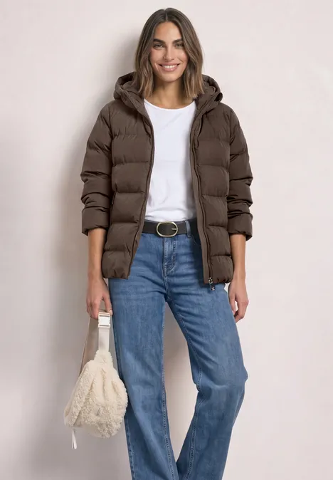 Kurze Jacke mit geklebter Steppung auburn brown Frau im braunen Steppmantel, weißem T-Shirt, blauen Jeans und flauschiger Tasche.