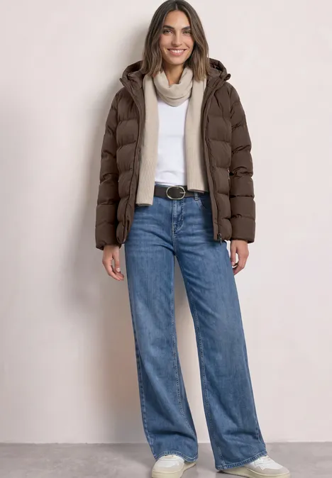 Kurze Jacke mit geklebter Steppung auburn brown Frau in brauner Steppjacke, weißem Pullover, Jeans und Schal, mit Gürtel lächelnd stehend.