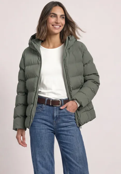 Kurze Jacke mit geklebter Steppung Somber Green Frau mit graugrüner Steppjacke, Kapuze, weißem Shirt, Jeans und Gürtel, lächelnd