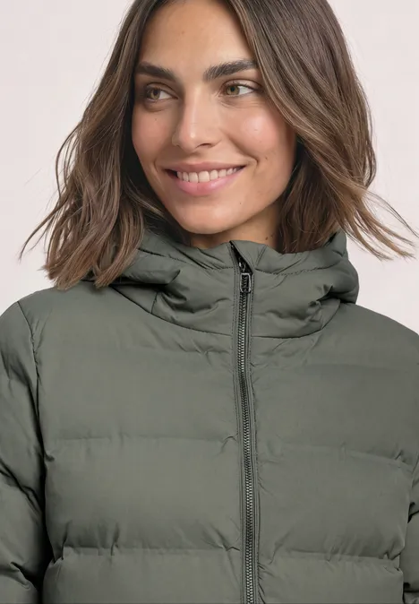Kurze Jacke mit geklebter Steppung Somber Green Frau in olivgrüner, gesteppter Winterjacke mit Kapuze, lächelnd.