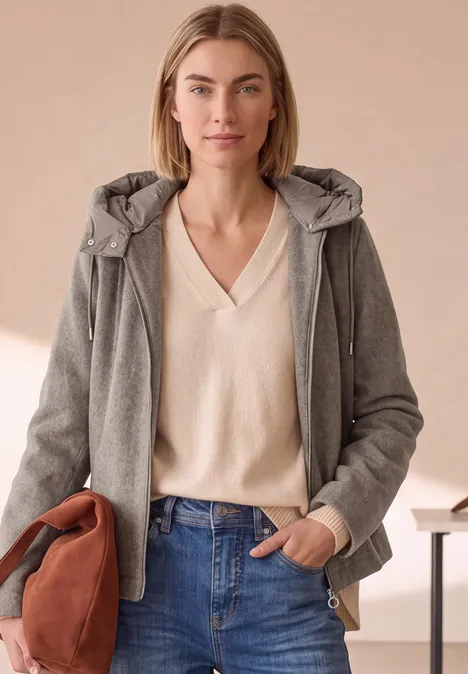 Jacke mit Wollanteil und abnehmbarer Kapuze Muddy Mocha Melange Frau mit grauer Jacke und cremefarbenem Pullover vor neutralem Hintergrund