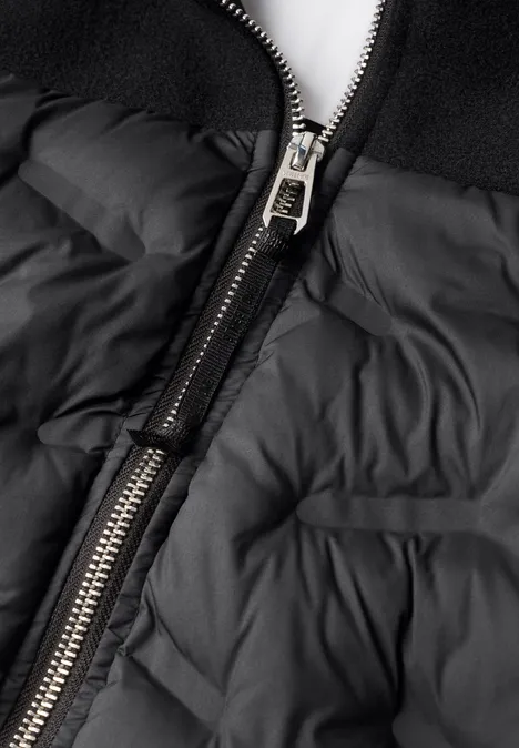 Schwarze Steppjacke aus nächster Nähe mit silbernem Reißverschluss.