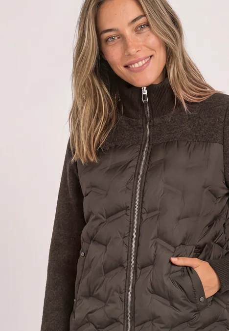 Femme souriante en veste marron matelassée avec fermeture éclair et manches en polaire.