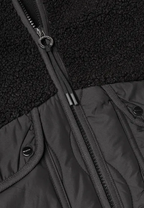 Mantel mit Strukturmix und Stehkragen Black Nahaufnahme eines schwarzen Jackenoberteils mit Teddy-Fleece, Nylonpasse und durchgehendem Reißverschluss.
