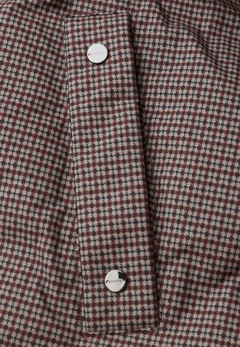 Jacke mit Kapuze und Steppmuster auburn brown Nahaufnahme eines rot-grau karierten Stoffes mit weißen Knöpfen an einer Knopfleiste.