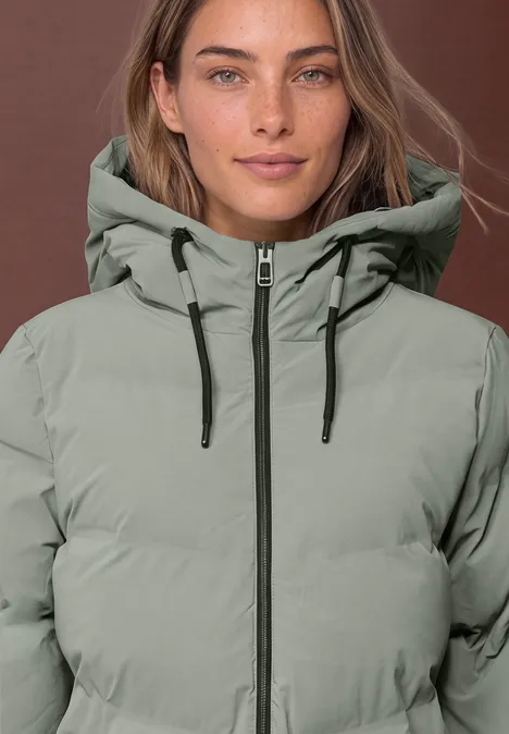 Veste matelassée à capuche et détails zippés Fresh Sage Femme portant une doudoune gris-vert clair à capuche et fermeture éclair.