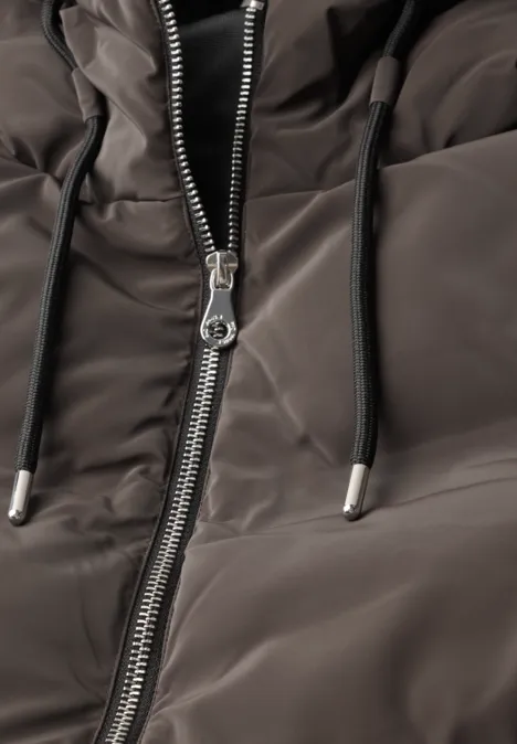 Close-up van een grijze gewatteerde jas met rits en capuchonkoordjes.