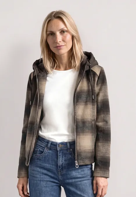 Jacke mit Wollanteil und abnehmbarer Kapuze auburn brown Frau mit blonder Mähne trägt eine karierte Jacke mit Kapuze, weißes Shirt und blaue Jeans.