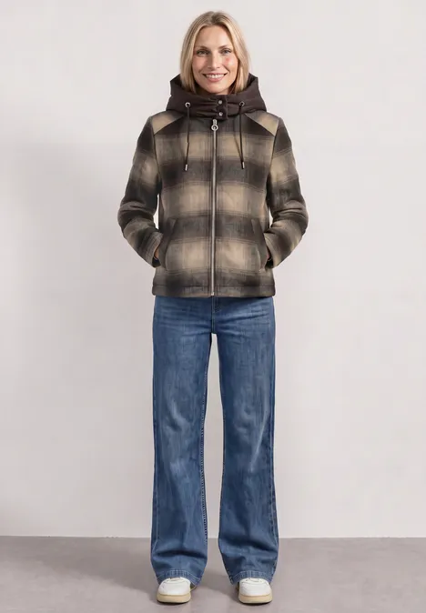 Jacke mit Wollanteil und abnehmbarer Kapuze auburn brown Frau in karierter, kurz geschnittener Kapuzenjacke und Schlagjeans vor neutralem Hintergrund.