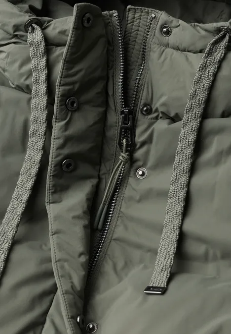 Lange Jacke mit Kapuze und Steppmuster Somber Green Nahaufnahme einer olivgrünen Steppjacke mit Reißverschluss und geflochtenen Zugbändern