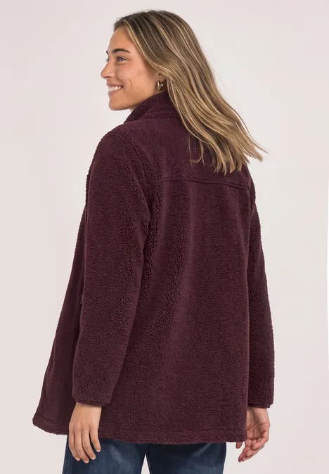 Frau mit schulterlangem Haar trägt eine bequeme, bordeauxrote Teddy-Fleecejacke, Rückansicht.