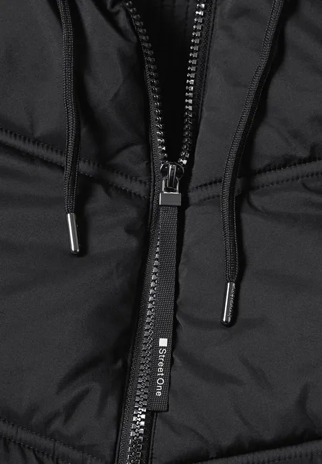 Gros plan sur une veste matelassée noire à capuche, fermeture éclair et cordons