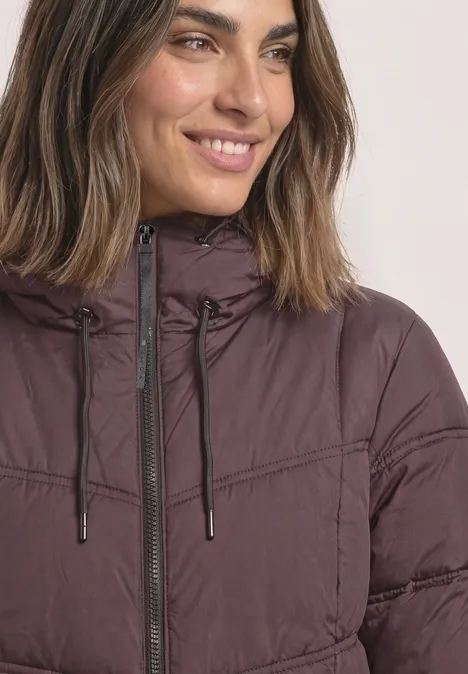 Frau in bordeauxfarbener Steppjacke mit Kapuze und Reißverschluss, lächelnd.