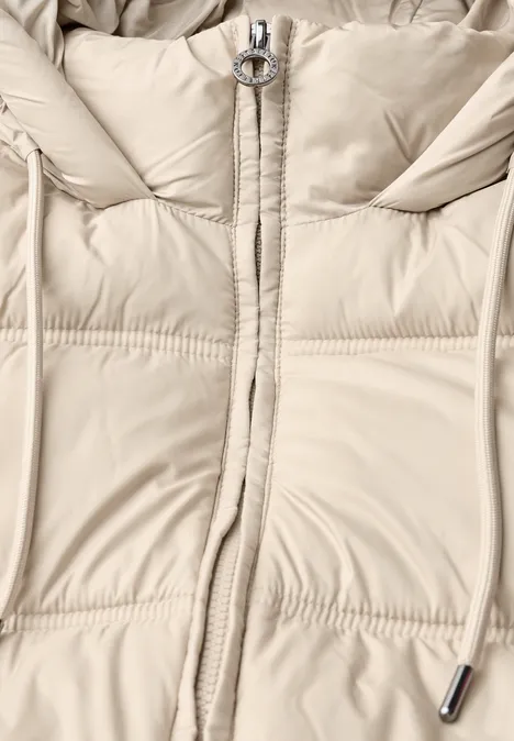 Veste matelassée à capuche barley beige Doudoune crème claire avec fermeture éclair à anneau et cordon de serrage au niveau de la capuche.
