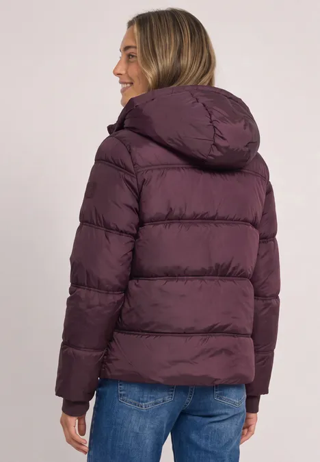 Vue de dos d’une personne portant une doudoune violette à capuche et un jean.