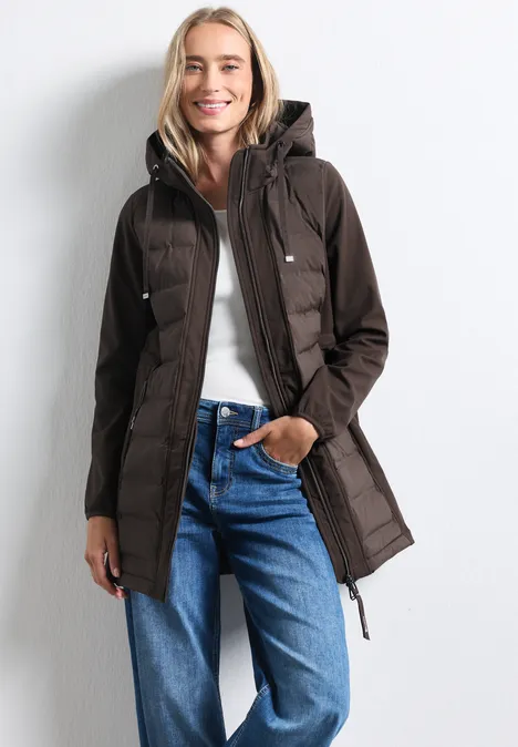 Frau trägt langen, braunen Parka mit Kapuze und Jeans.